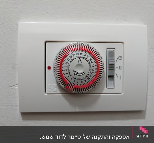 טיימר חשמלי עם חוגה ומתג על קיר